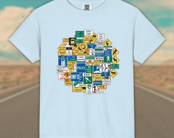 May include: A light blue short-sleeve t-shirt featuring a dense, circular collage of various colorful American road and traffic signs, including text like "POLICE," "INFO," "SPEED LIMIT 50," "HOSPITAL," and "$150 FINE," printed on the center of the chest.