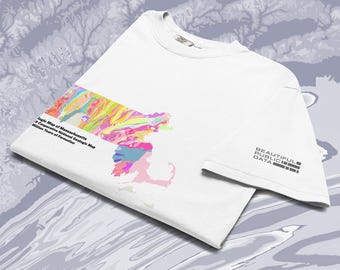 May include: A white short-sleeved t-shirt featuring a colourful geologic map of Massachusetts on the front. The graphic includes text reading Geologic Map of Massachusetts, US Cooperative National Geologic Map, and Million Years of Formation. The sleeve displays the text BEAUTIFUL PUBLIC DATA.