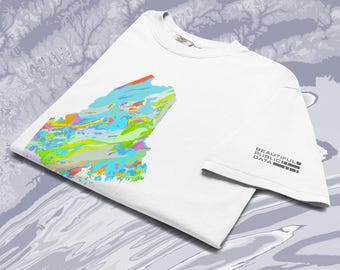 May include: A white short-sleeved t-shirt featuring a colourful, abstract geological map graphic on the front. The right sleeve displays the text "BEAUTIFUL PUBLIC DATA" in a black, blocky, sans-serif font arranged in a stacked, rectangular layout.