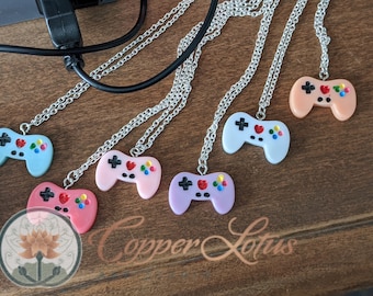 May include: Seven silver necklaces with colorful plastic game controller pendants. The controllers are in shades of pink, blue, purple, and peach. The text "Copper Lotus" is visible in the bottom center of the image.