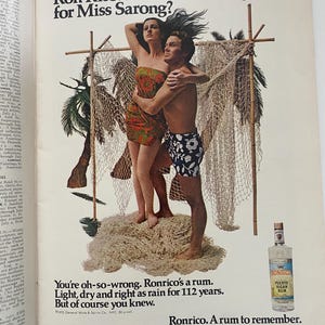 May include: A vintage advertisement for Ronrico Puerto Rican Rum featuring a couple in a tropical setting. The man is holding the woman, and they are standing on a pile of fishing nets. The text reads "Ronrico. A rum to remember." and "You're oh-so-wrong. Ronrico's a rum. Light, dry and right as rain for 112 years. But of course you knew."