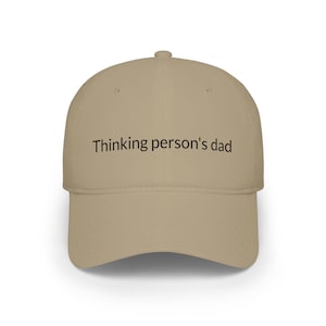 Può includere: Un cappellino da baseball beige con il testo nero Thinking person's dad stampato sul pannello frontale. Il cappellino presenta una corona strutturata, una visiera curva e un bottone sulla parte superiore, offrendo un design semplice e pulito.