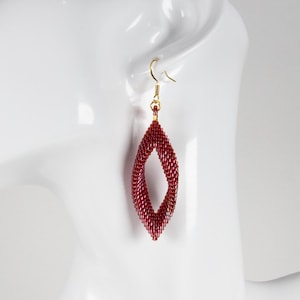 May include: Maroon beaded earrings in a teardrop shape, hanging from gold-colored hooks. The earrings are displayed on a white mannequin head. The logo "BEADED DRIP" is visible in the upper right corner.