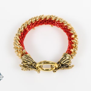 May include: A circular bracelet featuring a woven pattern of metallic gold and vibrant red beads. The ends of the bracelet are finished with detailed gold-toned dragon head metal caps that meet at a central gold ring clasp closure.