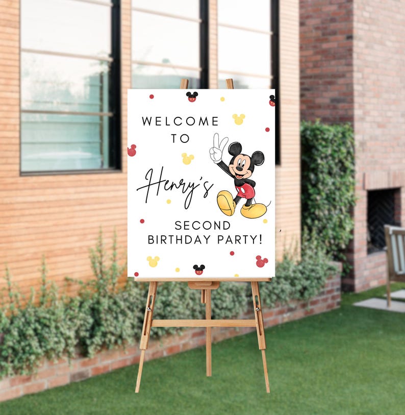 May include: Welcome to Henry's Second Birthday Party sign featuring a cartoon Mickey Mouse in red shorts and yellow shoes, waving with two fingers. The sign has a white background with red and yellow polka dots and Mickey Mouse ears.