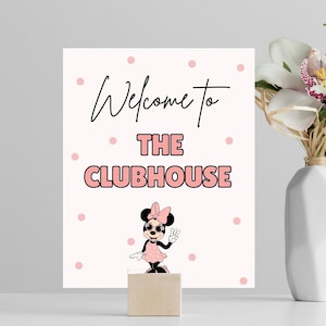 May include: A white sign with pink polka dots and black text that says "Welcome to The Clubhouse". A cartoon image of Minnie Mouse wearing sunglasses and a pink dress is below the text.