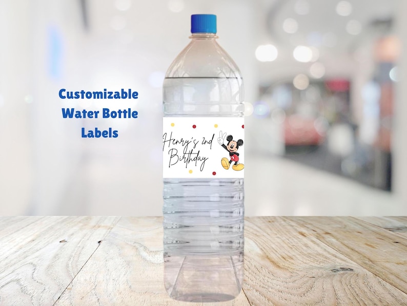 May include: A clear plastic water bottle with a label that says "Henry's 2nd Birthday" and features a cartoon image of Mickey Mouse. The label has red, yellow, and white polka dots.