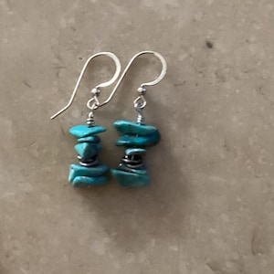 May include: A pair of silver earrings with turquoise stones. The stones are stacked and wrapped in silver wire.