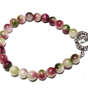 May include: A beaded bracelet featuring round, multi-colored beads in shades of pink, green, and white. The bracelet is secured with a silver-toned clasp. The beads are approximately 0.3 inches in diameter.