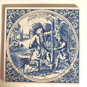 May include: Blue and white ceramic tile featuring a detailed illustration of two figures planting a tree, with the text "De Hovenier" at the top. The tile is framed by a floral border and includes the dates 1649-1712.