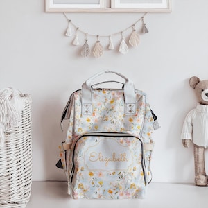 Portapañales ligero con diseño de flores azules para baby shower, ideal como regalo para guardería, gran capacidad, para viajes, con bolsillo frontal y espacio abierto.
