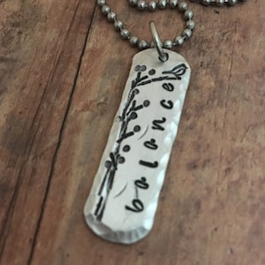 May include: Silver necklace with a rectangular tag that says "balance" with a floral design.