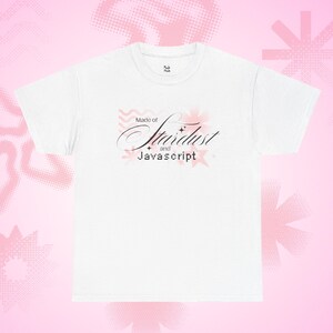 Może przedstawiać: Biała koszulka z napisem "Made of Stardust and Javascript" w ozdobnej czcionce i różowych akcentach. Koszulka ma okrągły dekolt i krótkie rękawy. Tło jest różowe z abstrakcyjnymi kształtami.