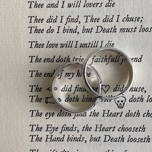 Pu&ograve; includere: Due fedi nuziali d'argento con le parole "faithfull" e "love" incise su di esse. Le fedi sono appoggiate su una pagina di un libro con una poesia sull'amore e la morte.