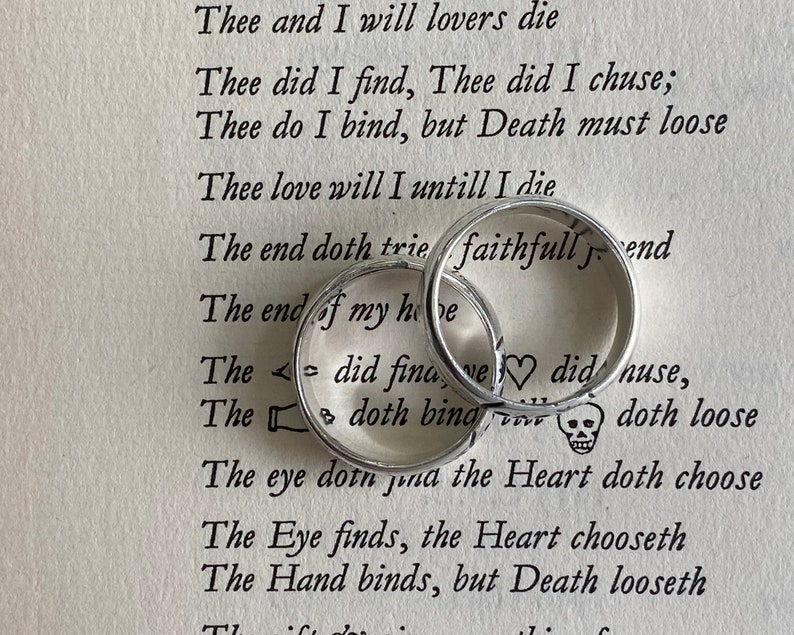Pu&ograve; includere: Due fedi nuziali d'argento con le parole "faithfull" e "love" incise su di esse. Le fedi sono appoggiate su una pagina di un libro con una poesia sull'amore e la morte.