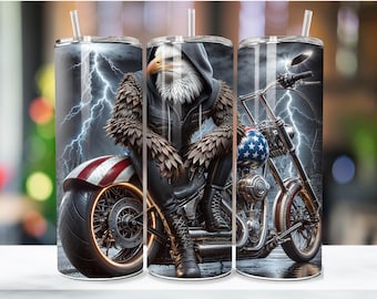 Op de afbeelding: Een roestvrijstalen tumbler met een ontwerp van een adelaar die een motorfiets rijdt met een Amerikaanse vlag. De adelaar draagt ​​een leren jack en heeft een woeste uitdrukking. De motorfiets is een klassieke chopper met een groot voorwiel en een lang, laag frame. De achtergrond is donkerblauw met bliksem.