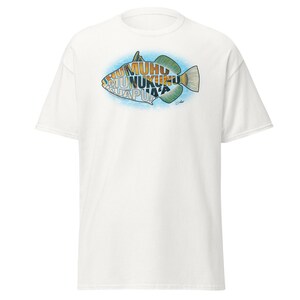 May include: White t-shirt with a colourful fish design and text. The fish is outlined in black with green, yellow, and blue accents. The text inside the fish is in a stylized font. The shirt is made of a soft, comfortable material.