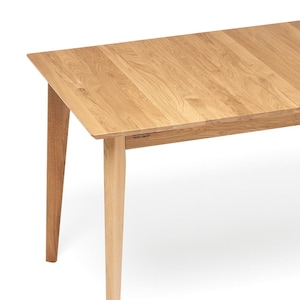 May include: A light-colored wooden dining table with a rectangular top and four tapered legs. The table has a natural wood grain finish and a simple, modern design. The text "WOOD CONCEPT" is visible on the side of the table.