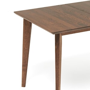 May include: A rectangular wooden table with a dark brown finish. The table has four tapered legs and a simple, modern design. The wood grain is visible on the tabletop and legs.