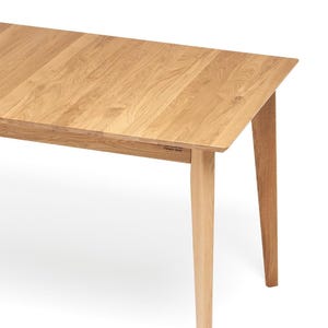 May include: A light brown wooden dining table with a rectangular top and four tapered legs. The surface displays a natural wood grain pattern with visible knots and textures. The table features a clean, straight-edged design with a smooth finish.
