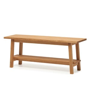 May include: A rectangular wooden bench featuring a natural light brown wood grain finish. The bench has a flat top surface, four sturdy legs, and a lower shelf positioned between the legs, providing additional storage space beneath the seat.