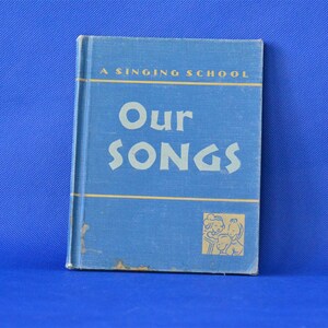 May include: A blue book titled "Our Songs" with the words "A Singing School" printed above the title. The book cover features a small illustration of three children singing.