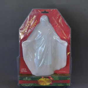 May include: A white plastic Jesus Christ tree topper in a red and green box with the text "Jesus Christ Tree Topper" and "Have a Very Merry Christmas!"