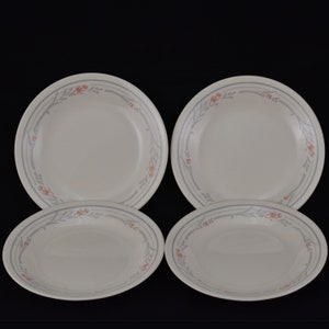 May include: Set of four white ceramic dinner plates with a grey and orange floral design around the rim.