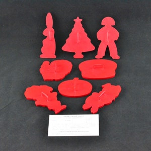 Puede incluir: Conjunto de ocho cortadores de galletas de plástico rojo con forma de árbol de Navidad, conejo, muñeco de nieve, calabaza, corona, pavo, sombrero y hombre de jengibre.