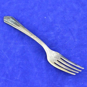 May include: A silver fork with a decorative handle. The fork is on a blue background.