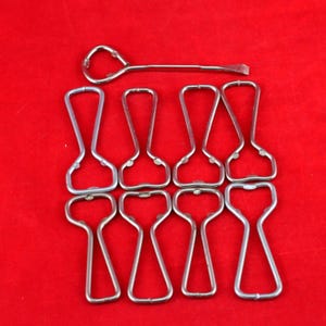 May include: A selection of silver bottle openers against a red backdrop. The image shows a long, thin opener with a loop at one end and a flat edge, plus eight standard bottle openers.