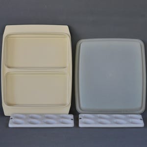 May include: A vintage beige plastic divided serving dish with a matching lid and two white egg holders. The serving dish has two compartments. The lid is square and light gray. The egg holders have oval indentations.