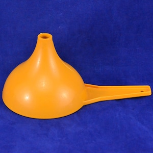 Puede incluir: Embudo de plástico naranja con un mango largo. El embudo tiene una abertura ancha y un pico estrecho.