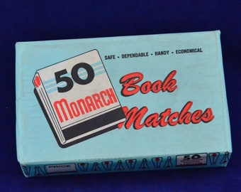 Può includere: Una scatola blu di 50 fiammiferi Monarch Book. La scatola ha testo rosso e bianco che dice "50 Monarch Book Matches". La scatola ha anche un'immagine rossa e bianca di un libro di fiammiferi.