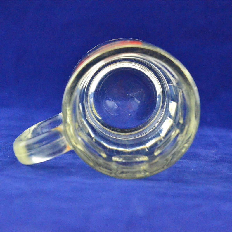 May include: A clear glass beer mug with a handle. The mug has a textured surface and is empty.