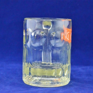 May include: A clear glass beer mug with a textured surface. The mug has a handle and is designed for holding beverages.