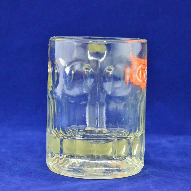 May include: A clear glass beer mug with a textured surface. The mug has a handle and is designed for holding beverages.