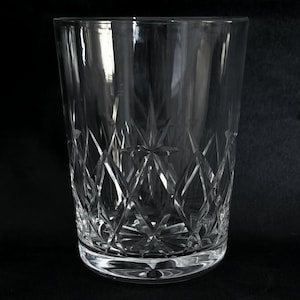 May include: A clear glass tumbler with a cut crystal design. The glass has a wide base and straight sides.
