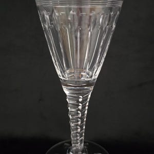 Peut inclure: Un verre à vin en verre transparent avec une longue tige torsadée et un bol large et évasé. Le bol présente un motif décoratif en verre taillé.