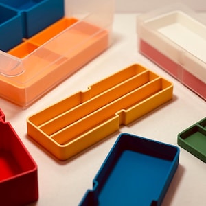 Peut inclure: Assortiment de boîtes de rangement en plastique de différentes couleurs avec différents compartiments. Les boîtes sont en plastique durable et léger et sont parfaites pour organiser de petits objets.
