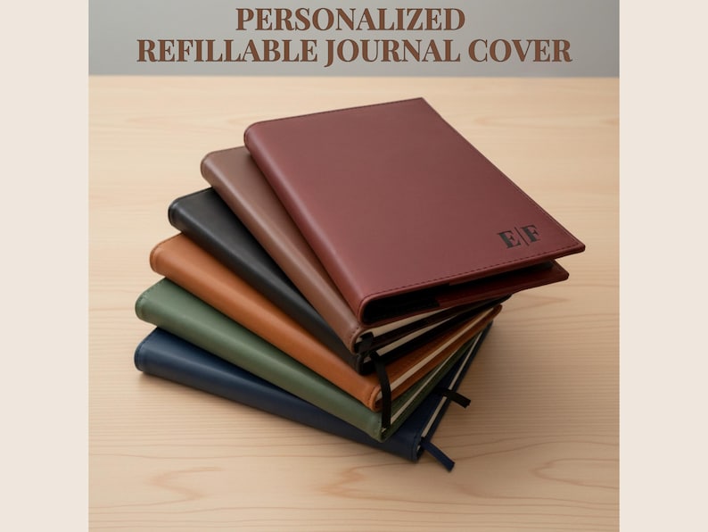 May include: A stack of personalized refillable journal covers in various colors, including burgundy, brown, black, tan, green, and navy blue. The top journal is burgundy with initials "EF" embossed. The text "PERSONALIZED REFILLABLE JOURNAL COVER" is at the top.