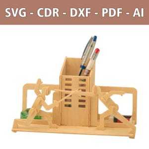 May include: A light-colored wooden desk organizer featuring a central rectangular pen holder flanked by two stylized figures engaged in a fencing match. The structure includes slots for pens and small items, with the text SVG - CDR - DXF - PDF - AI visible.