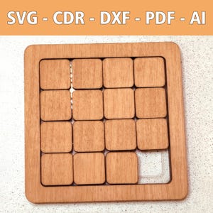 Könnte beinhalten: Holzpuzzle mit rechteckigem Rahmen und sechzehn quadratischen Teilen. Ein Teil fehlt, wodurch eine transparente Kunststoffbasis sichtbar wird. Der Text "SVG - CDR - DXF - PDF - AI" steht oben.