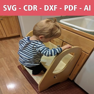 May include: A young child standing on a wooden step stool with a light brown finish. The stool has a cutout in the back for easy access and a small handle on the side. The child is wearing a blue and white striped shirt and black pants. The stool is in front of a wooden cabinet with a white sink.