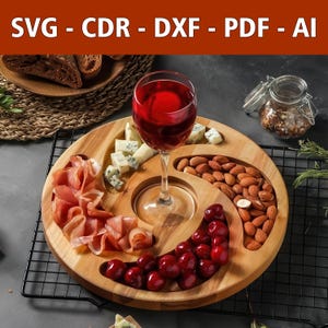 Puede incluir: Una bandeja de servir de madera con cuatro secciones para queso, carne, fruta y nueces. Un vaso de vino tinto se encuentra en el centro de la bandeja. La bandeja está hecha de madera natural y tiene un aspecto rústico.