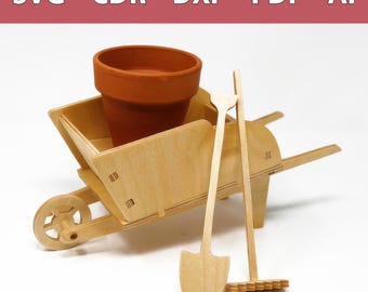 May include: A wooden toy wheelbarrow with a terracotta flower pot, a small wooden shovel, and a rake. The wheelbarrow is made of light wood and has a brown wooden wheel. The shovel and rake are also made of light wood.