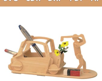 Op de afbeelding: Een bureau-organizer van licht hout in de vorm van een auto met een figuur die deze van achteren duwt. De structuur bevat vakjes voor pennen en potloden, met de tekst SVG - CDR - DXF - PDF - AI bovenaan. Een kleine gum ligt op de basis.