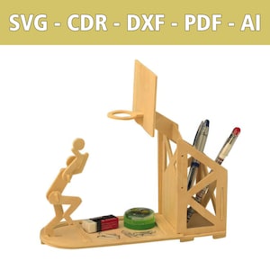 May include: A light-colored wooden desk organizer shaped like a basketball court with a hoop, a player figure, and a pen holder. The base holds a small eraser and a green container. Text at the top reads SVG - CDR - DXF - PDF - AI.