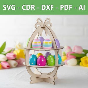 May include: A two-tiered wooden egg stand with a bow-shaped top, holding colorful decorative eggs with stripes and polka dots. The top tier features striped eggs, while the bottom tier displays solid-colored eggs with white polka dots. Text reads SVG - CDR - DXF - PDF - AI.