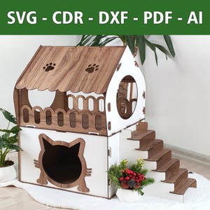 Puede incluir: Una casa para gatos de madera blanca y marrón con una entrada en forma de gato, un balcón y un conjunto de escaleras. La casa tiene un techo con huellas de patas y una ventana redonda.